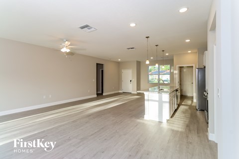 A spacious room with a light-colored floor and walls, and a ceiling fan with lights.