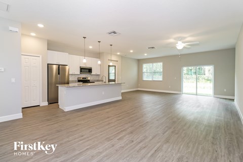A spacious kitchen with wooden floors and a refrigerator.