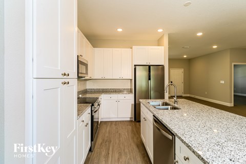 A kitchen with white cabinets and a granite countertop.
