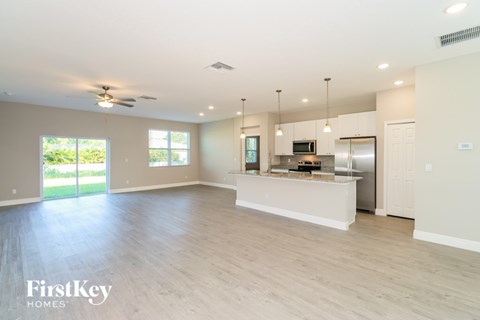 A spacious kitchen and living room with a sliding glass door leading to a backyard.
