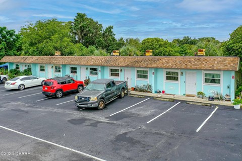 A parking lot with a blue building and several cars parked in front.