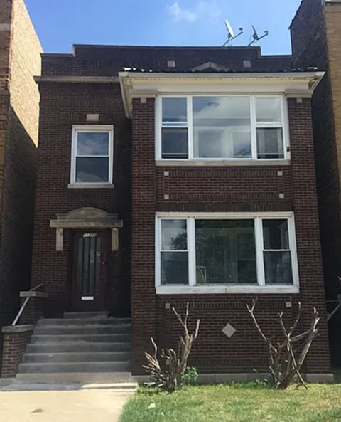 A brick house with a black door and a small porch.