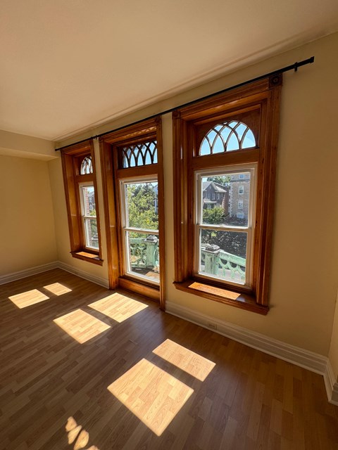 A room with wooden floors and three windows.