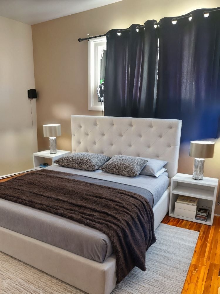 A bedroom with a large bed and a white headboard.