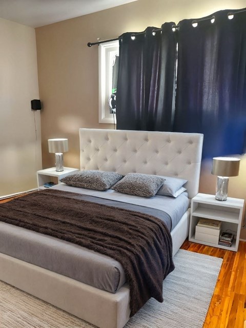 A bedroom with a large bed and a white headboard.