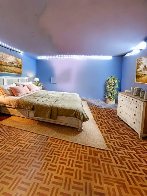 A bedroom with a bed, dresser, and a painting on the wall.