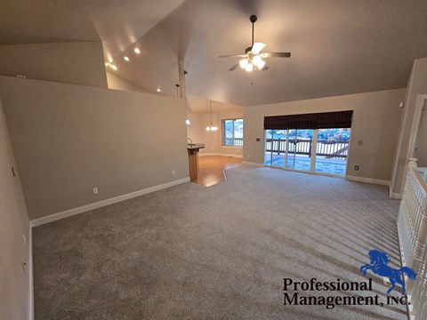 A spacious room with a carpeted floor and a ceiling fan.