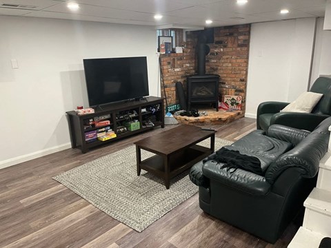 A living room with a black leather couch, a wooden coffee table, and a brick fireplace.