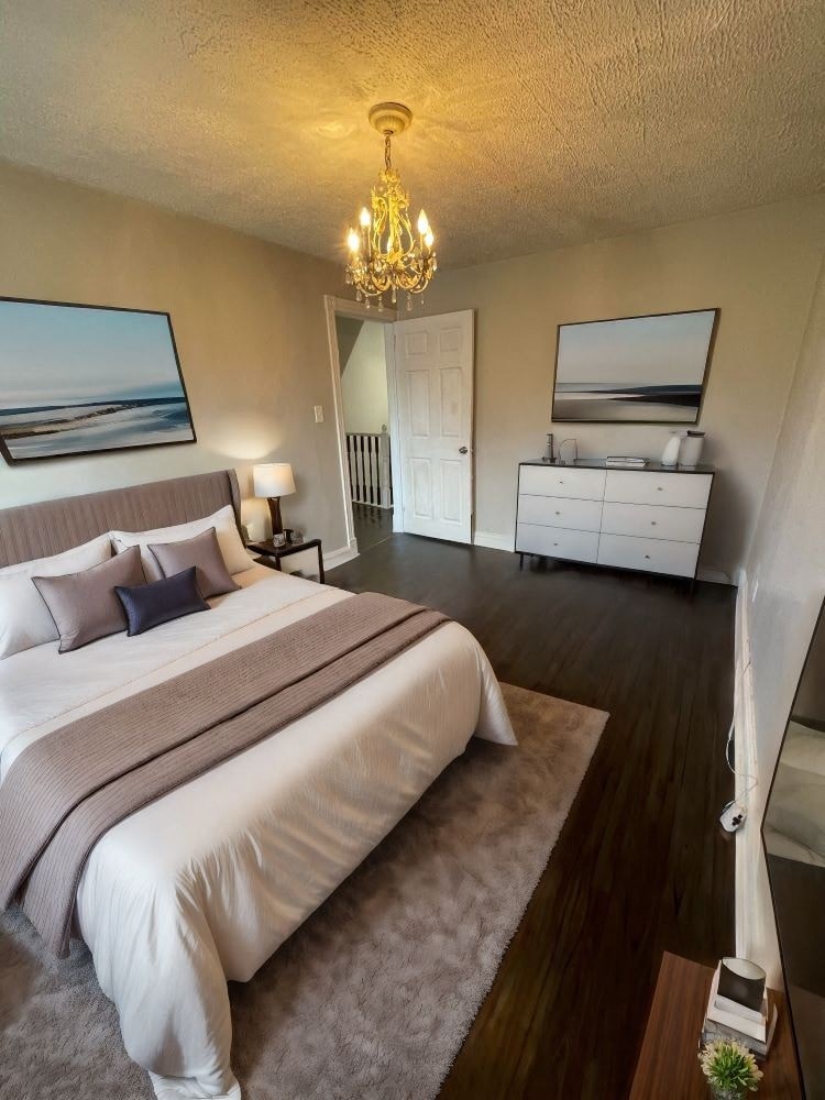 A bedroom with a large bed and a chandelier.