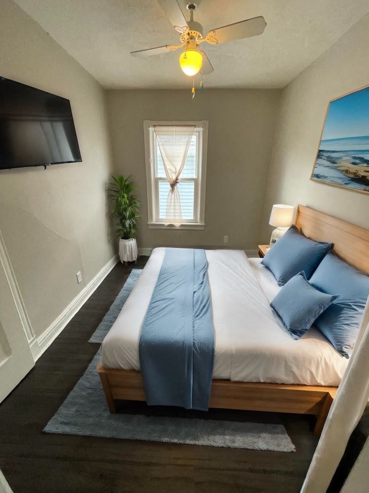 A bedroom with a bed, a ceiling fan, and a window.