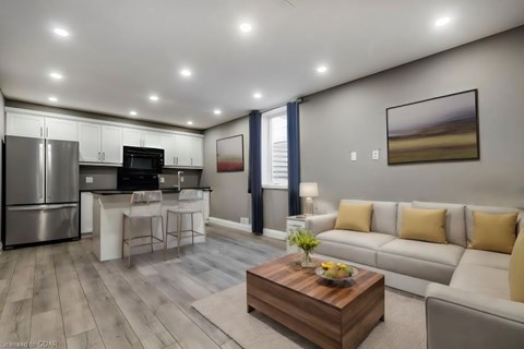 A modern kitchen with a refrigerator, microwave, and oven, with a dining area and a living room with a couch and a coffee table.