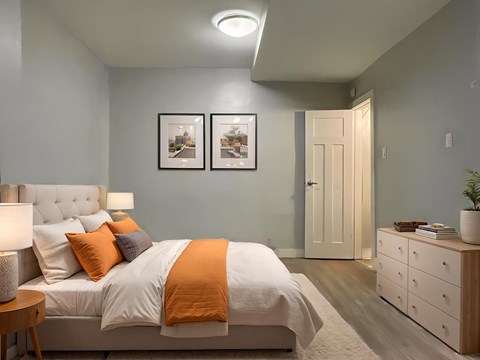 A bedroom with a bed, nightstand, and two pictures on the wall.