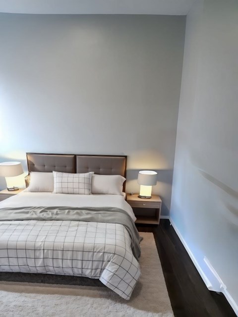 A bed with a white comforter and two lamps on bedside tables.