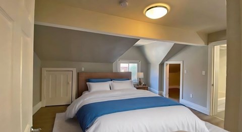 A bedroom with a bed, nightstand, and lamp.