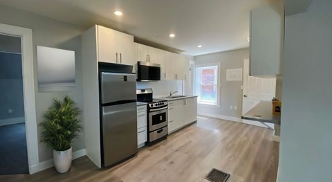 A modern kitchen with stainless steel appliances and wooden flooring.