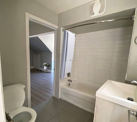 A white toilet is in a bathroom with a white tub and sink.