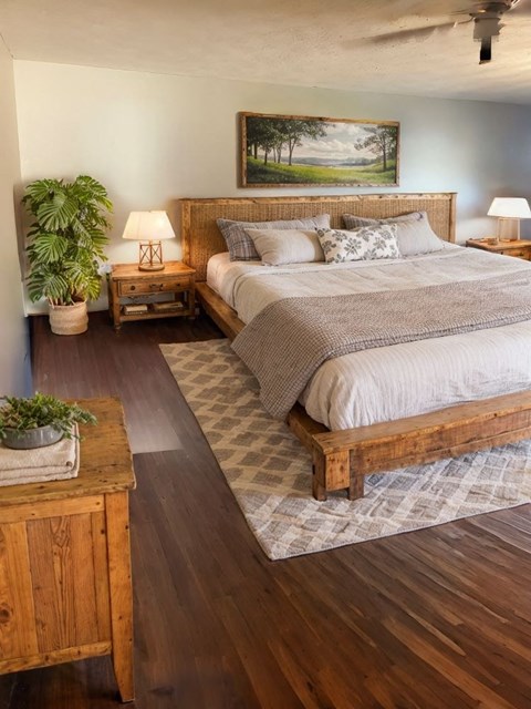 A bedroom with a large bed and a painting on the wall.