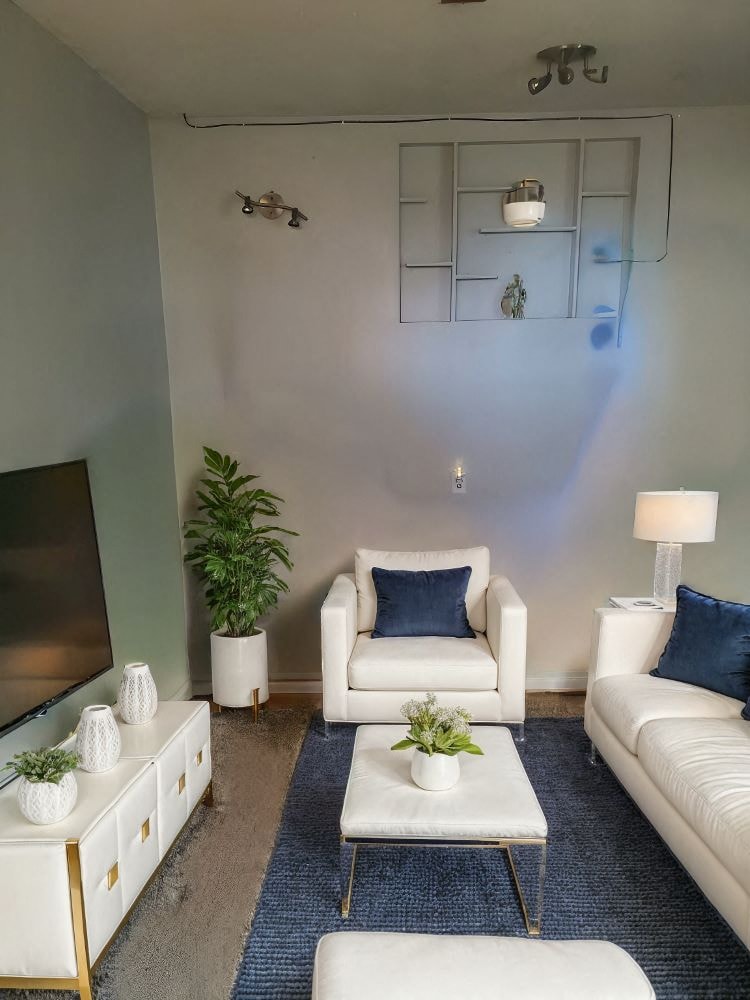 A living room with a white couch, a white coffee table, and a white TV.