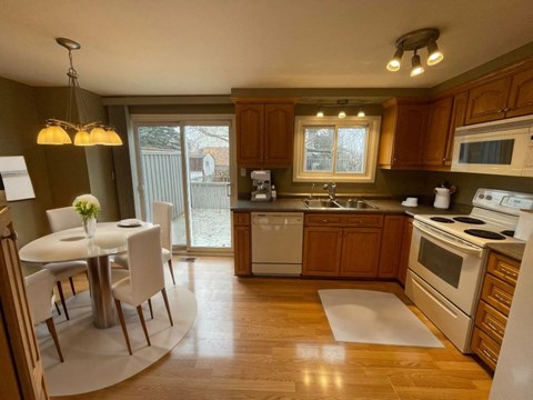 A kitchen with wooden cabinets and a white table.