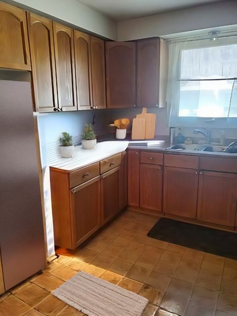 A kitchen with wooden cabinets and a tiled floor.