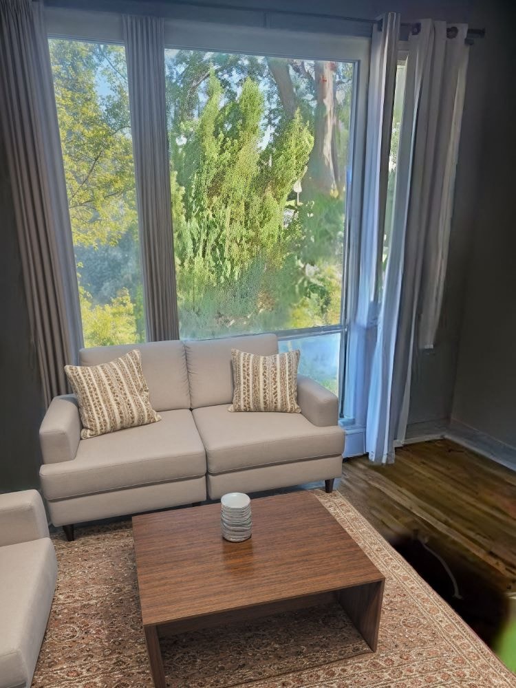 A living room with a couch, a coffee table, and a window with curtains.
