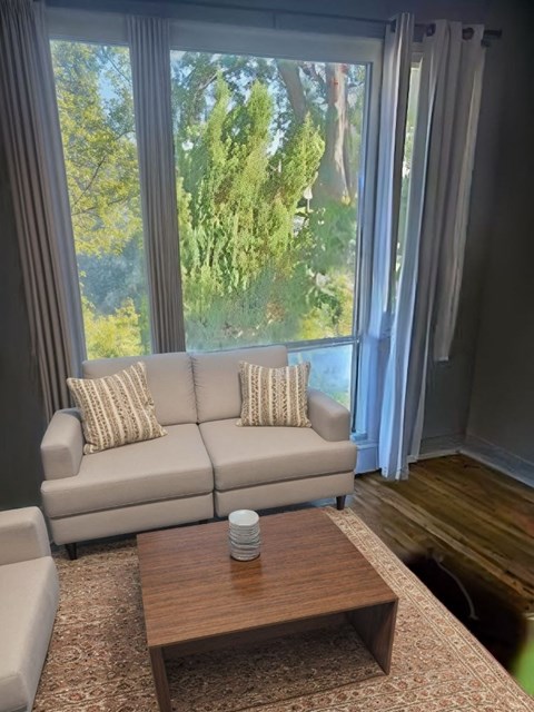 A living room with a couch, a coffee table, and a window with curtains.