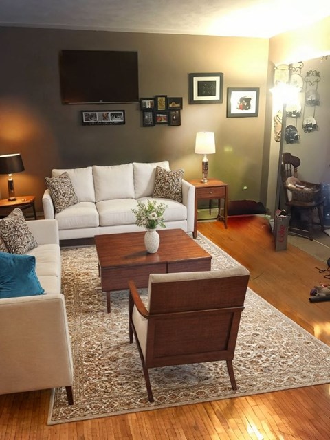 A living room with a white couch, a coffee table, and a rug.