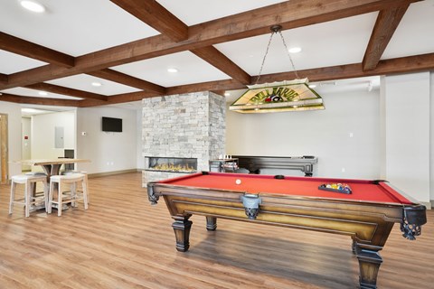 A pool table is in the middle of a room with a fireplace and a TV.