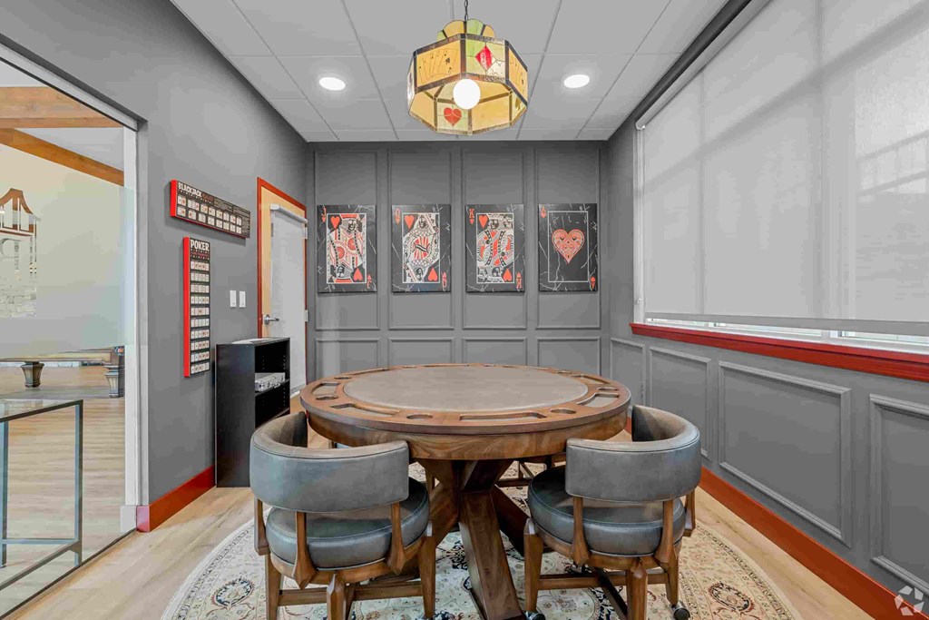 A conference room with a round wooden table surrounded by grey chairs.