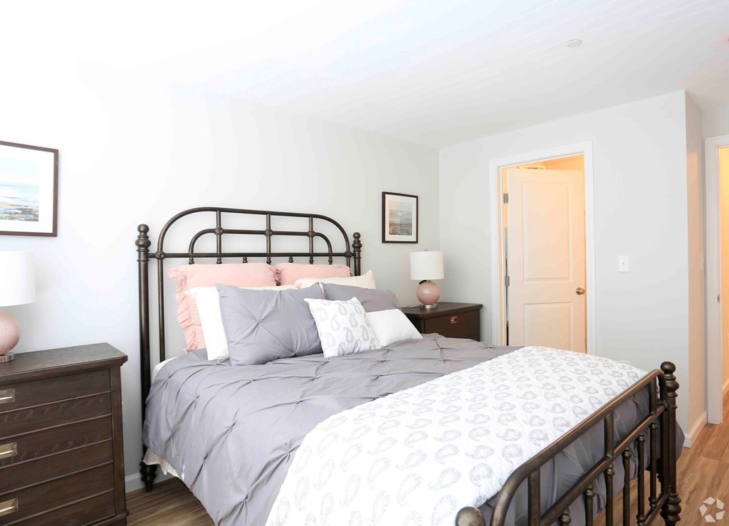 A bedroom with a large bed and a wooden dresser.