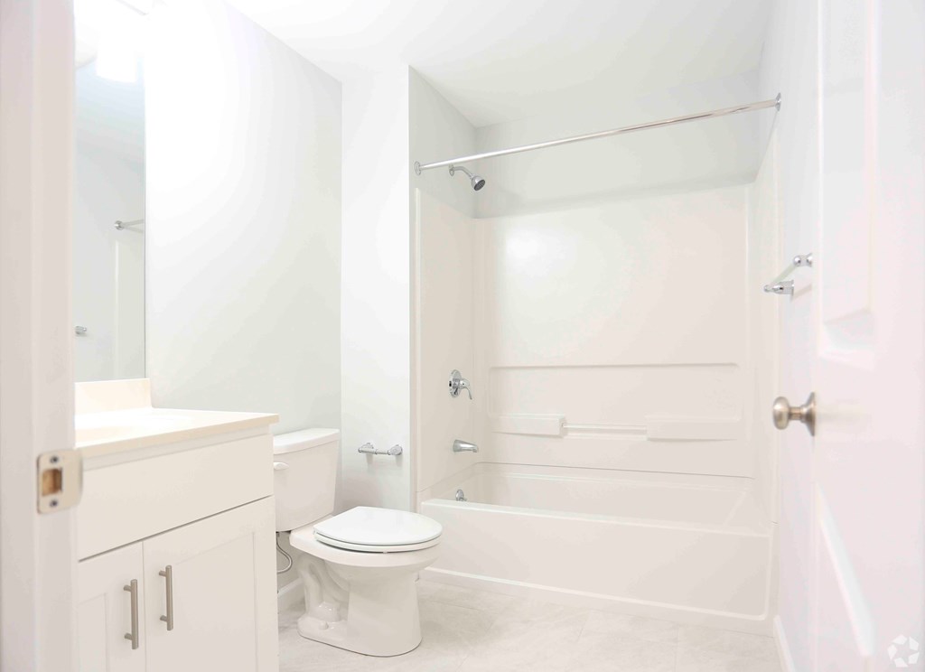 A white bathroom with a toilet, sink, and shower.