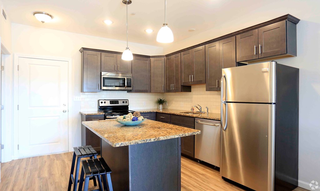 A kitchen with a stainless steel refrigerator and microwave above the counter.