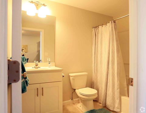 A white bathroom with a toilet, sink, and shower.