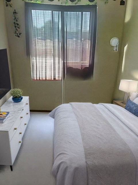 A bedroom with a bed, nightstand, and window with blinds.