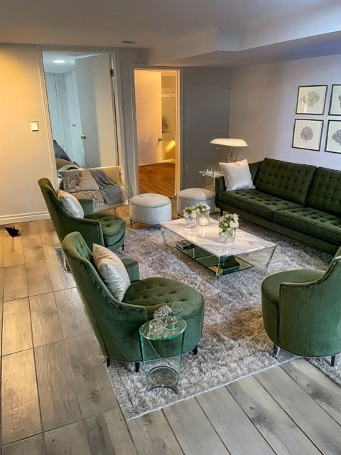 A living room with green couches and a glass coffee table.