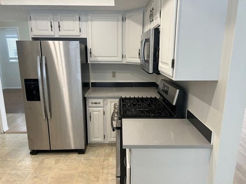 A kitchen with a stainless steel refrigerator and white cabinets.