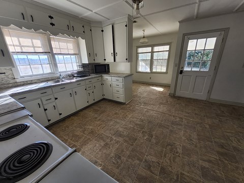 A kitchen with a tiled floor and a stove top oven.