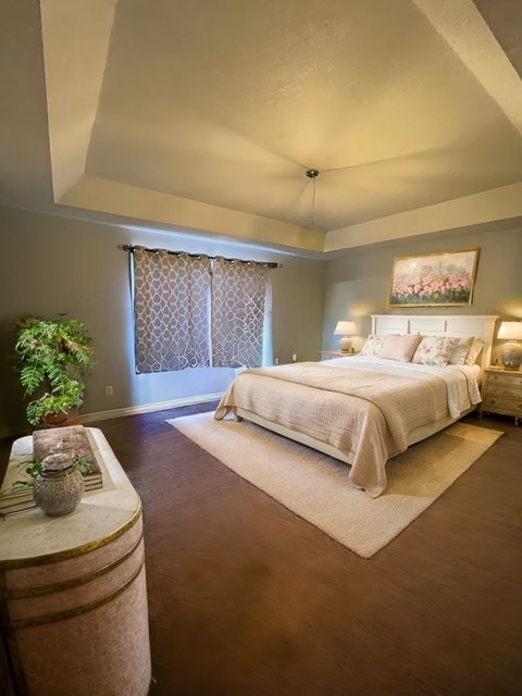 A bedroom with a large bed and a plant on the side table.