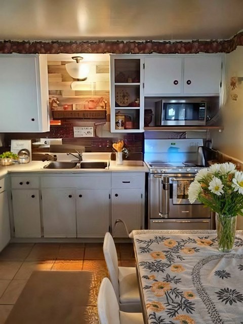 A kitchen with a table and chairs and a vase of flowers.