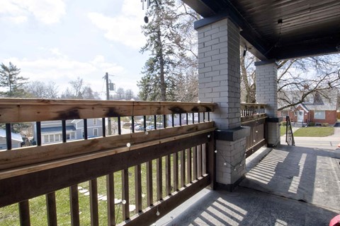 A wooden deck with a railing and a brick pillar.