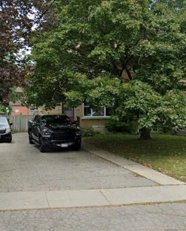 A black car is parked on a driveway.