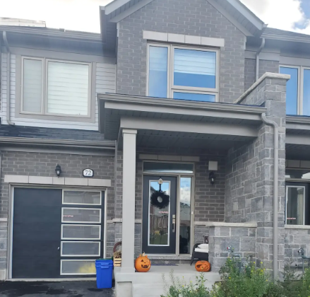 A grey house with a black door and a window with blinds.