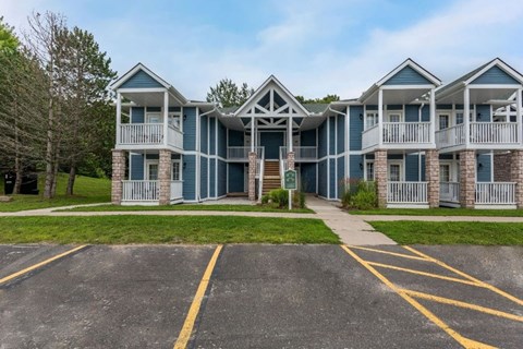 A row of blue and white houses with a parking lot in front.