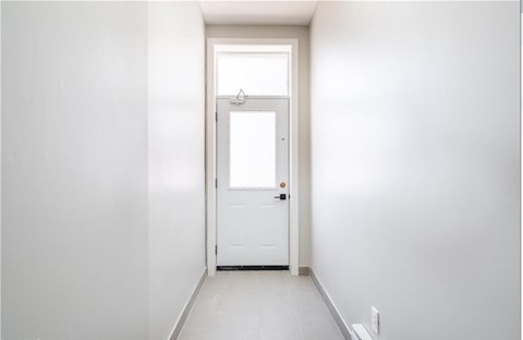 A white door is in a white hallway.