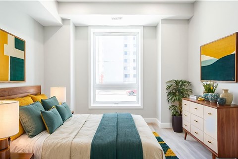 A bedroom with a bed, nightstand, and a painting on the wall.