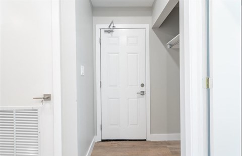 A white door is in a hallway with a light switch on the wall.