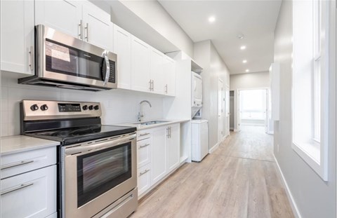 A modern kitchen with white cabinets and stainless steel appliances.