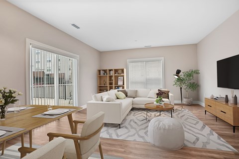 A modern living room with a white sofa, wooden coffee table, and a large window with blinds.