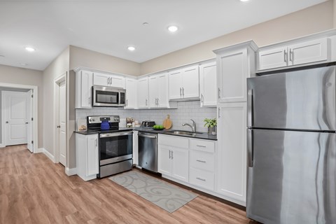 A kitchen with white cabinets and a stainless steel refrigerator.