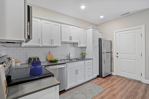A kitchen with white cabinets and a black stove top.